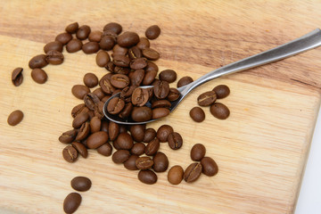 On the kitchen board are coffee beans and a metal teaspoon. concept - morning coffee