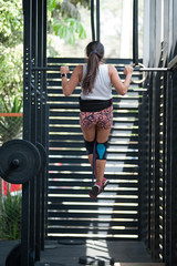 Fototapeta na wymiar Young Latina woman doing a pull-up at the gym