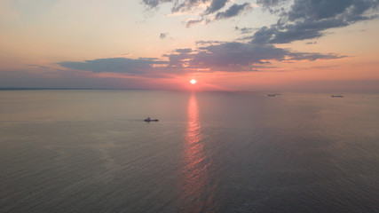 Naklejka premium Dawn on the sea. The warm sun rises above the water. Photographed from the drone. Aerial photo shooting