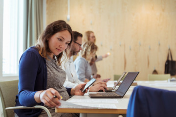 Pregnant businesswoman with smart phone and laptop reading document in office meeting