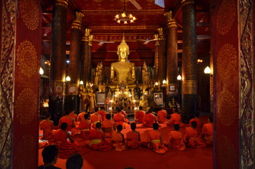 LUANG PRABANG, LAOS - MARCH 20 2018: Group of monks pray in Wat May Suwannaphumaham Temple in Laos