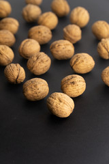Walnuts in shell lying on black surface, side view. Healthy nuts and seeds background.