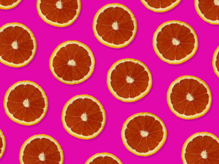 Creative pattern made of red oranges. top view of colorful fruit pattern of fresh red orange slices on pink colorful background. 