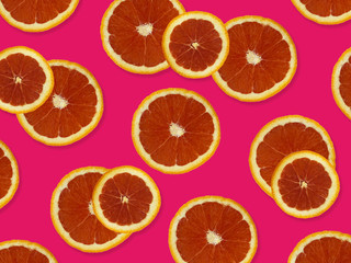 Creative pattern made of red oranges. top view of colorful fruit pattern of fresh red orange slices on pink colorful background. 