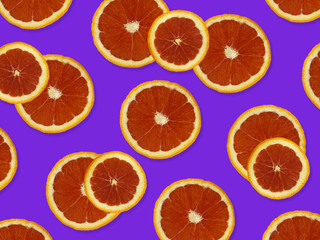 Creative pattern made of red oranges. top view of colorful fruit pattern of fresh red orange slices on purple colorful background. 