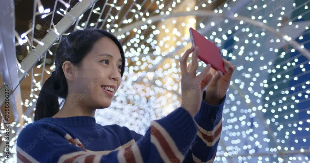 Wall mural woman take photo on cellphone with the beautiful lighting decoration in city at night