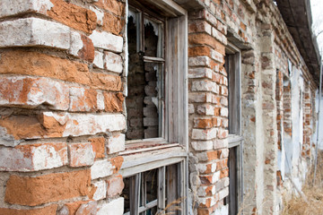 View of broken windows and a red brick wall in an abandoned old house