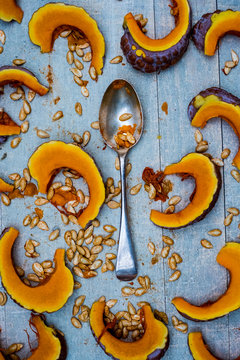 High angle close up of silver tablespoon and slices of pumpkin on blue background.