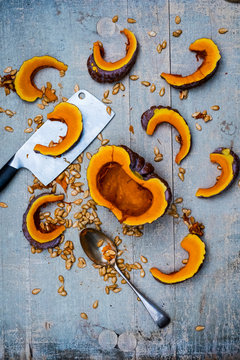 High angle close up of cleaver, silver tablespoon and slices of pumpkin on blue background.