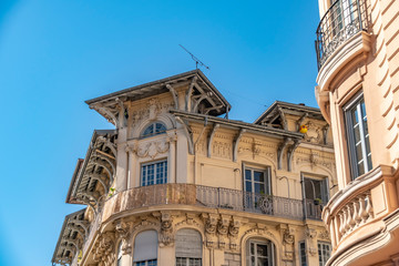 View to the decorated facade of a historic house in Nice, France. You can see the typical windows, balconies and shutters of a Mediterranean cityscape.