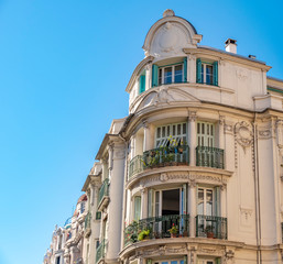 Obraz premium View to the decorated facade of a historic house in Nice, France. You can see the typical windows, balconies and shutters of a Mediterranean cityscape.
