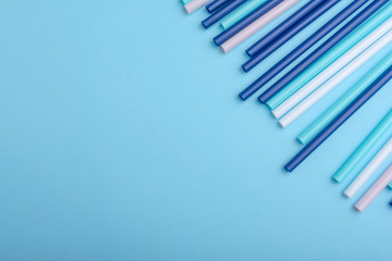 Plastic tubes can use as background in design. Multicolored cocktail straws lying on a blue background with copy space for text. Top view.