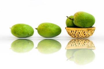 Raw organic kesar mangoes isolated on white in a basket along with some on surface with its reflection also.