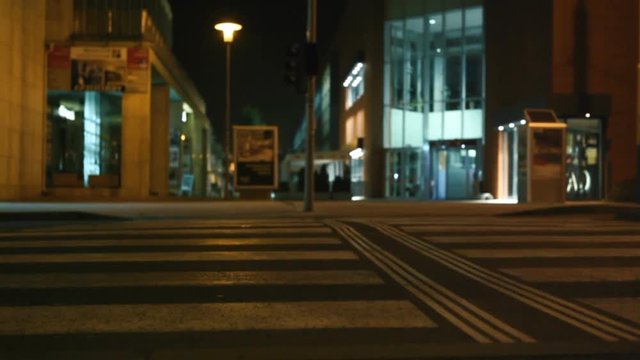 Car passing well-lit pedestrian crossing at night. Pedestrian safety concept.