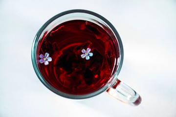 Mug with red hibiscus tea with small flowers
