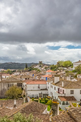 Fototapeta na wymiar View of the fortress and Luso Roman castle of Óbidos, with buildings of Portuguese vernacular architecture and sky with clouds, in Portugal