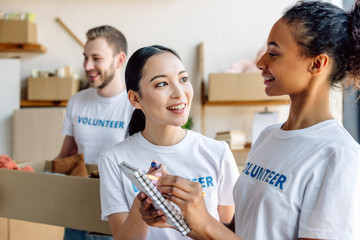 selective focus of pretty multicultural volunteers talking while holding notebook