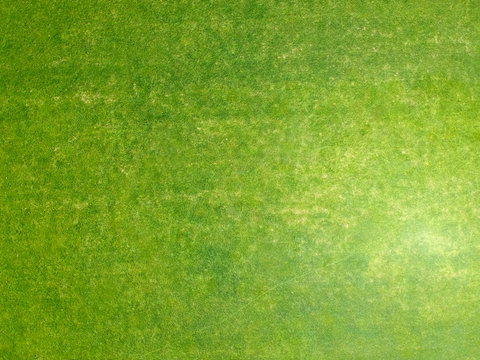 Aerial view of a large patch of freshly cut, healthy green grass. Minimalistic state of the art background. Visible strokes of the grass cut and direction lines.