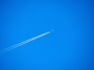 Traces of exhaust gases from the aircraft engine. White stripes and a plane on a bright blue sky. Modern jet plane with white condensation track. Travel concept. Beautiful background or wallpaper.
