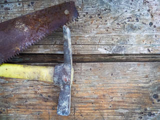  hammer and rusty hand saw on old wooden boards.