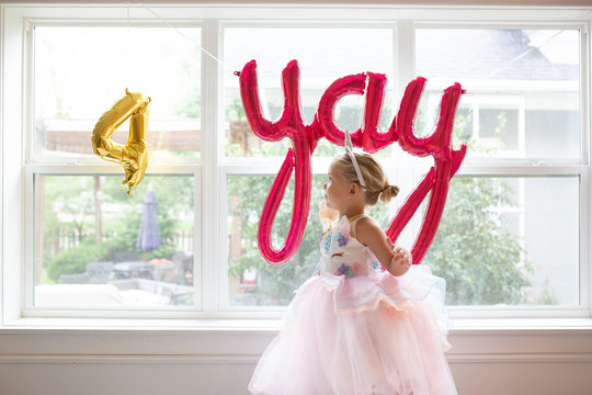 side view of cute girl in fancy dress by window for birthday