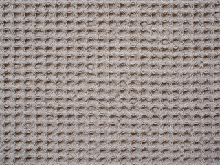 Close-up of brown textile texture, background and wallpaper. Texture of brown knitted fabric. Surface of a fleece towel. Texture of brown fabric textile upholstery of furniture. High-quality macro.