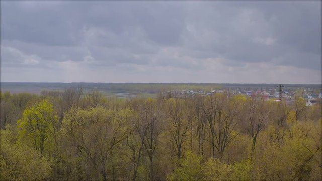 Beautiful village in Russia view from a height.. Green and bright, spring landscape. View of the city and the mountain from the field of flowering trees and young foliage. Juicy fresh grass and vegeta