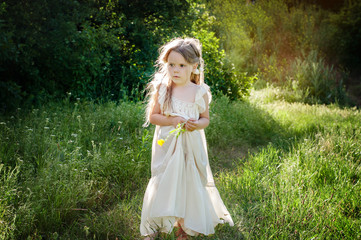 Obraz na płótnie Canvas Beautiful little girl in a long white dress. Carefree childhood.