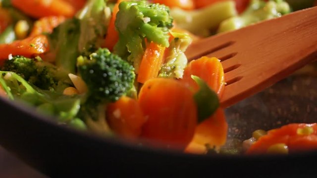 Close up view of steaming frying pan and tossing up mixed vegetables in slow motion. Vegetarian lifestyle, delicious, being on a diet. Healthy food, frying vegetables, organic products