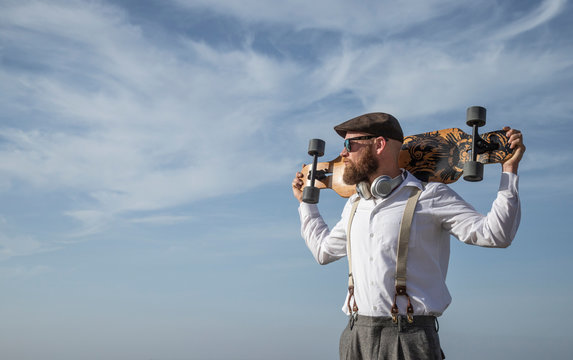 Bearded man with longboard on his shoulders looking at distance