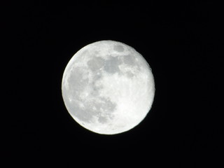Fototapeta premium Genova, Italy - 03/22/2019: An amazing photography of the full moon over the city of Genova by night with a great clear sky in background and some stars