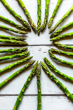 Green asparagus spears building heart on wood