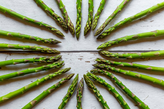 Green asparagus spears building heart on wood