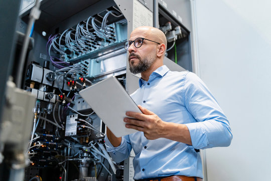 Businessman with tablet at machine in factory