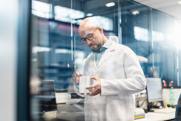 Technician wearing lab coat examining workpiece