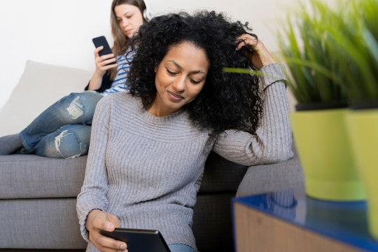 Friends relaxing at home, using mobile devices