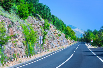 Beautiful asphalt freeway, motorway, highway without traffic in southern mountains forest landscape. Summer sunny weather. Travel road concept. Island Cres in the Adriatic Sea. Croatia.