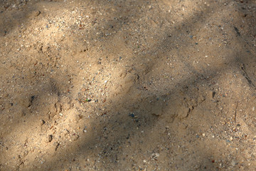 Uneven textured surface of a mixture of dirty sand and small stones