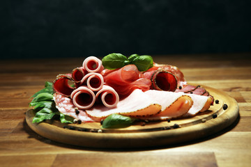 Food tray with delicious salami, pieces of sliced ham, sausages,salad and vegetable. Meat platter with selection