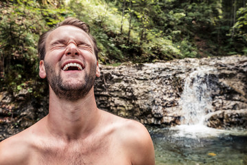 Germany, Upper Bavaria, Bavarian Prealps, lake Walchen, young man is laughing in a torrent