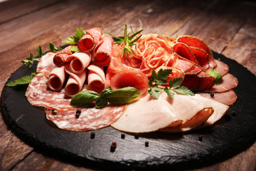 Food tray with delicious salami, pieces of sliced ham, sausages,salad and vegetable. Meat platter with selection