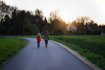 Fototapeta premium the sisters go along the empty road in the evening