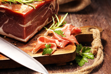 Italian prosciutto crudo or jamon with rosemary. Raw ham on wooden board