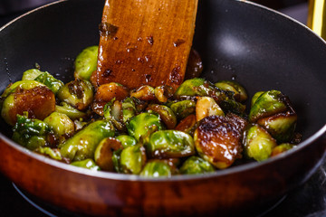 young woman fries Brussels sprouts on a frying pan
