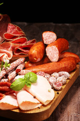 Food tray with delicious salami, pieces of sliced ham, sausages,salad and vegetable. Meat platter with selection