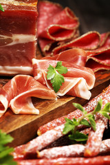 Food tray with delicious salami, pieces of sliced ham, sausages,salad and vegetable. Meat platter with selection