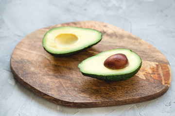 Two halves of avocado on a wooden board