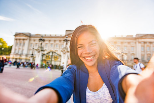 Travel selfie vlogger live streaming video online asian tourist woman social media influencer taking photo at Buckingham Palace London, UK. Europe summer vacation people lifestyle.