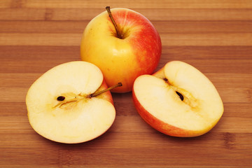 Naklejka na ściany i meble Whole apple and cut in half apple on cutting board