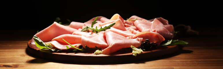 Sliced ham on wooden background. Fresh prosciutto. Pork ham proscuitto sliced.